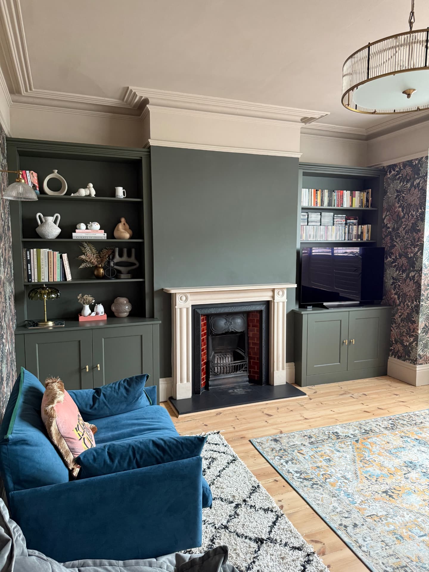 Dark green alcove cabinetry with bookshelves and media storage either side of a fireplace