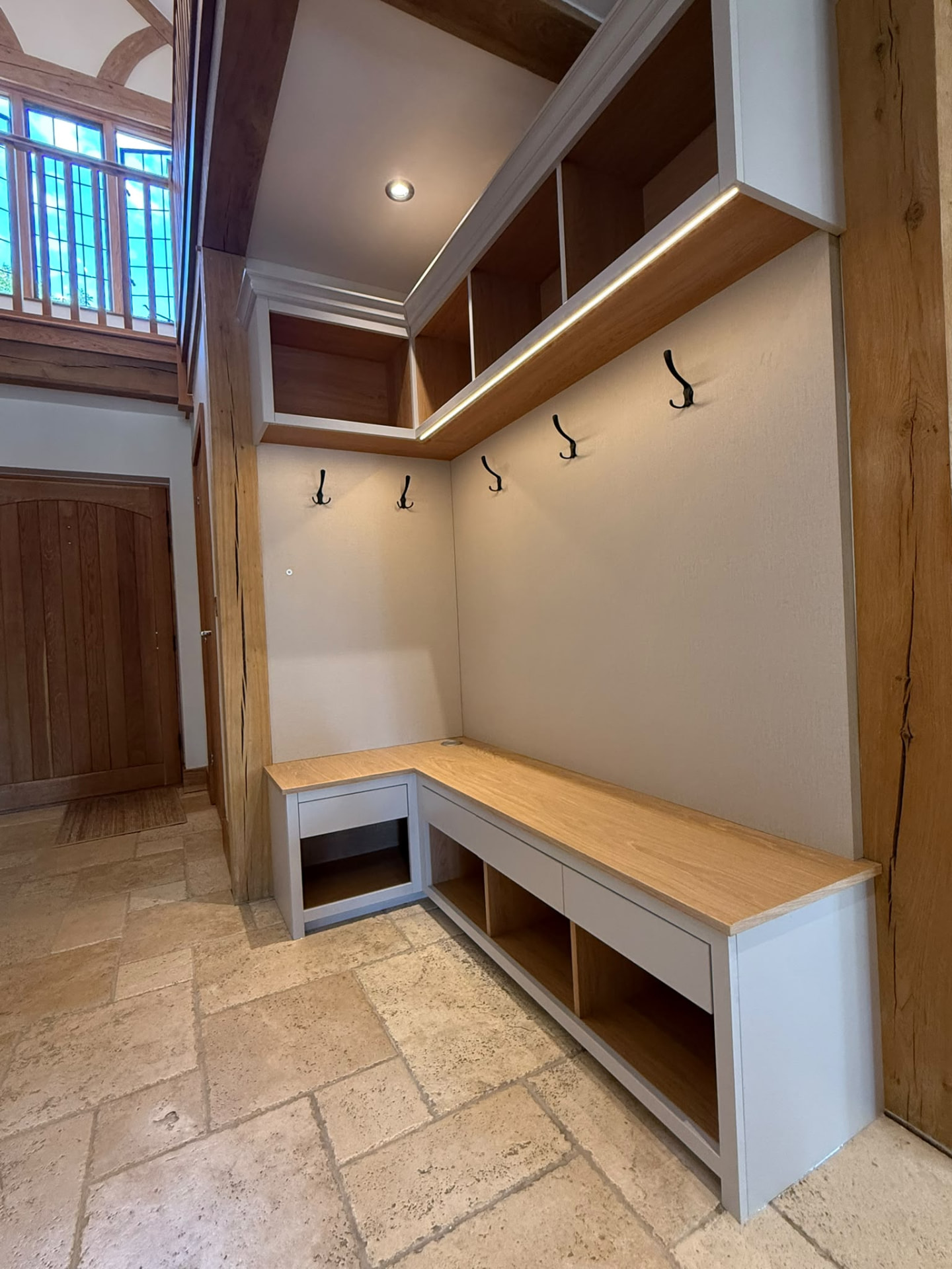 Fitted boot room bench and cubby storage in grey painted joinery with oak tops and lit shelving